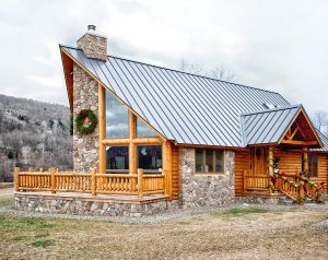 A log home decorated for the holidays with greenery and red ribbon