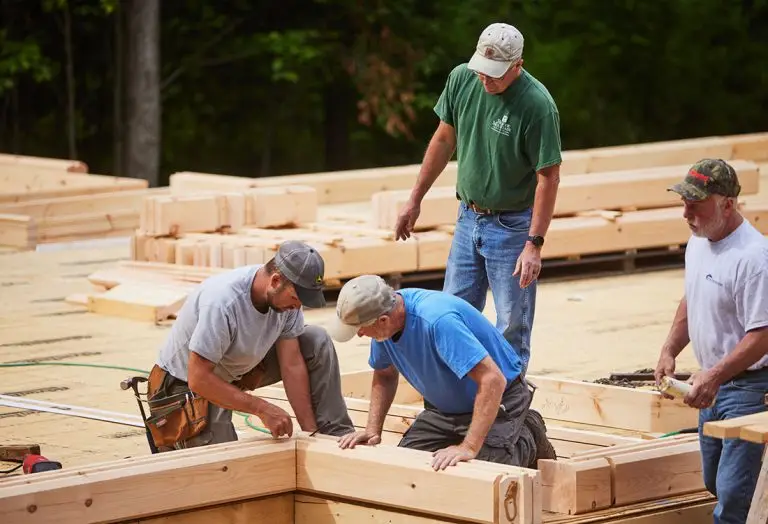 Beaver Mountain field technician working with a builder to lay the first course of logs on a custom home site.